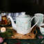 Théière en porcelaine et feuilles vertes