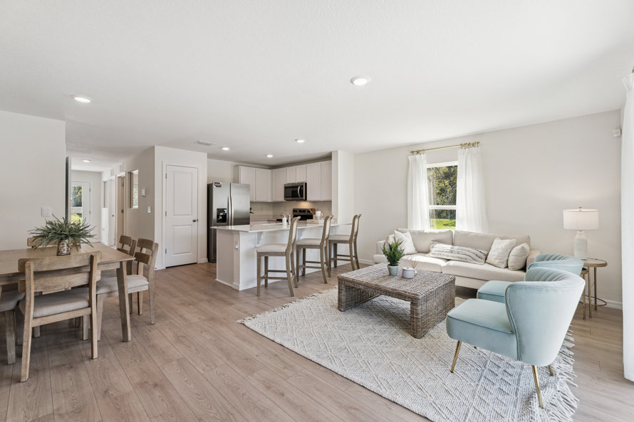 Open-concept kitchen, dining, and living room with wood floors and white walls.