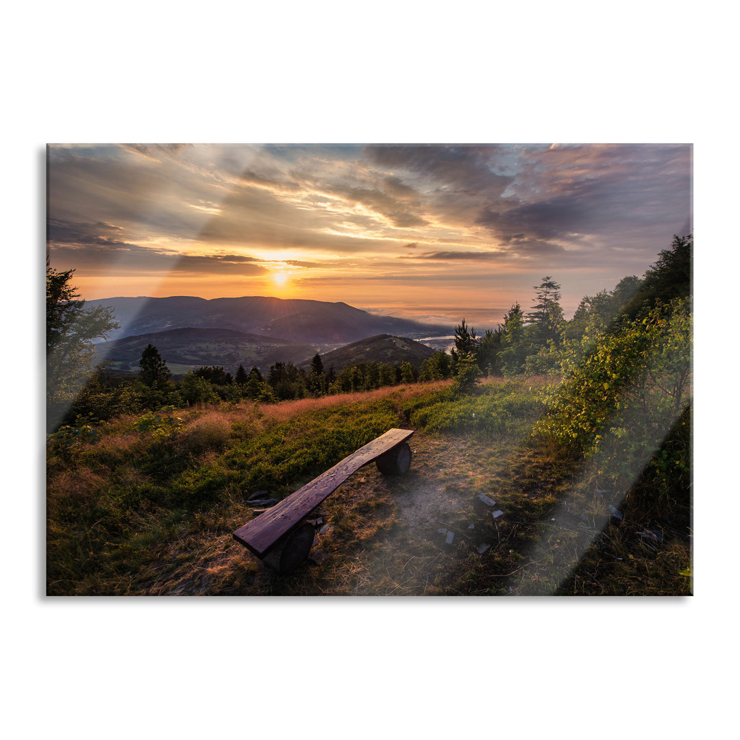 Glasbild Bank auf einem Berggipfel bei Sonnenuntergang