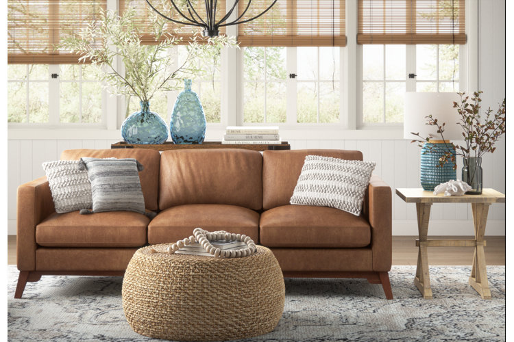brown leather sofa with a braided jute coffee table and blue glass vases