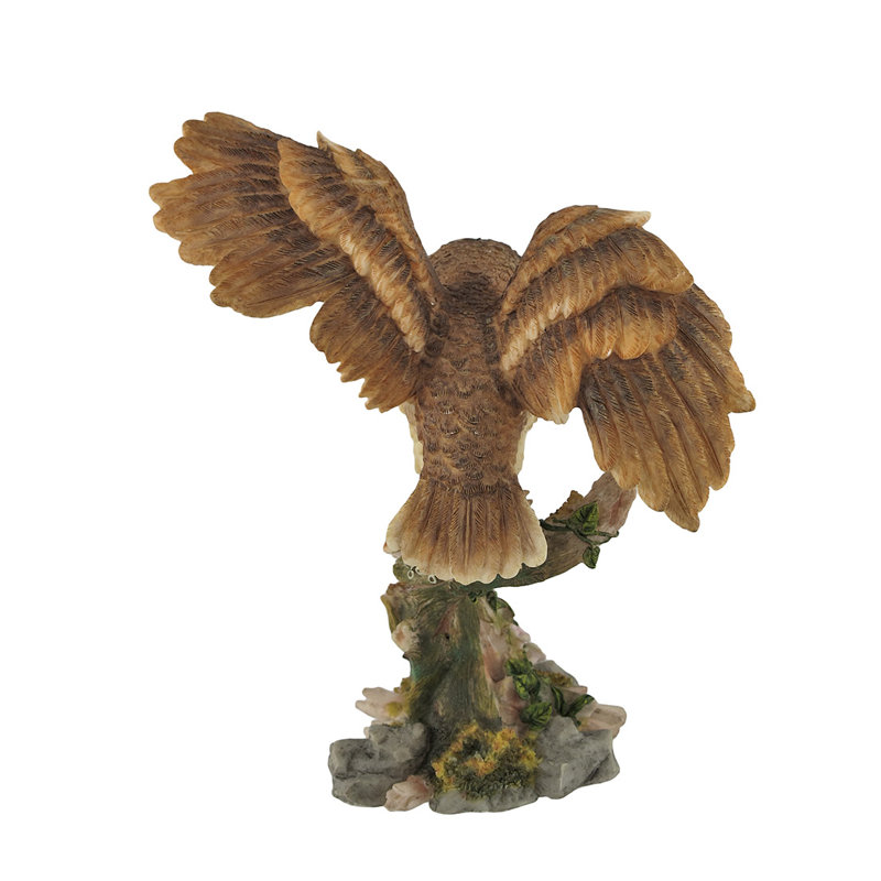 Statue de hibou déployant des ailes sur un perchoir