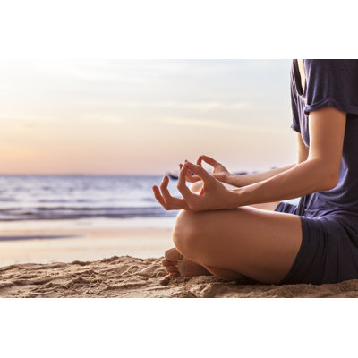 Young Woman Practicing Yoga On The Beach At Sunset
