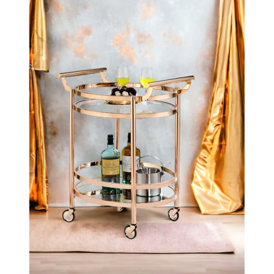 Chariot de service ovale en verre transparent et or rose avec 2 tablettes de rangement ouvertes, une tablette supérieure trempée de 5 mm, des poignées en métal à base de miroir de 3 mm, des roulettes, des roulettes en plastique pour le plancher