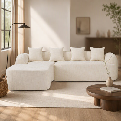 Canapé en forme de L en chenille beige qui s'agence bien avec n'importe quel salon. Il est doté d'une éponge hautement élastique pour une assise confortable, d'accoudoirs courbés et de quatre coussins décoratifs.