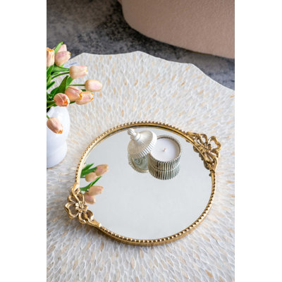 Plateau de service rond en fer avec cadre orné au fini doré et surface réfléchissante réfléchissante pour une présentation élégante et fonctionnelle.