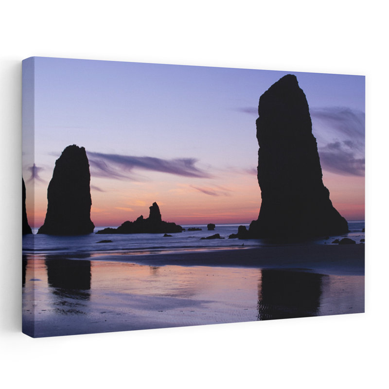 Silhouettes Of Rock Formations At Sunset At Cannon Beach Oregon USA by Dan Merkel - Wrapped Canvas Print