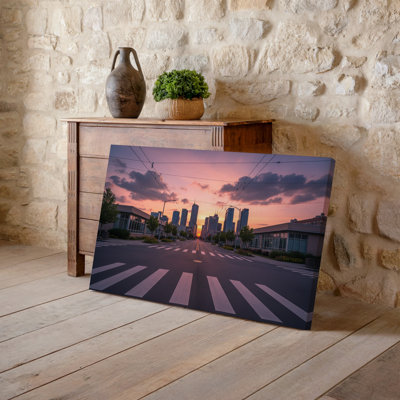 Canvas A Serene Urban Street Scene At Sunset Featuring A Wide Wall Art Empty Road Lined With Low Rise Buildings And Modern Skyscrapers Canvas Wall Art