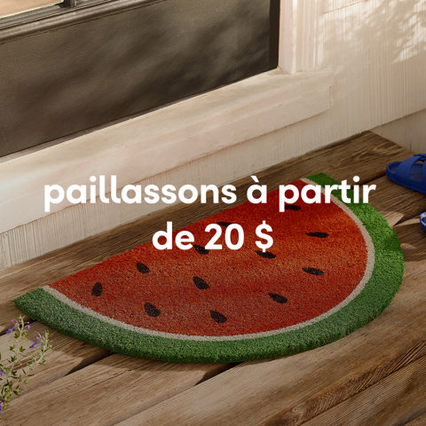 Un paillasson en coco en demi-cercle conçu pour ressembler à une tranche de pastèque rouge sur un porche en bois à partir de 20 $.