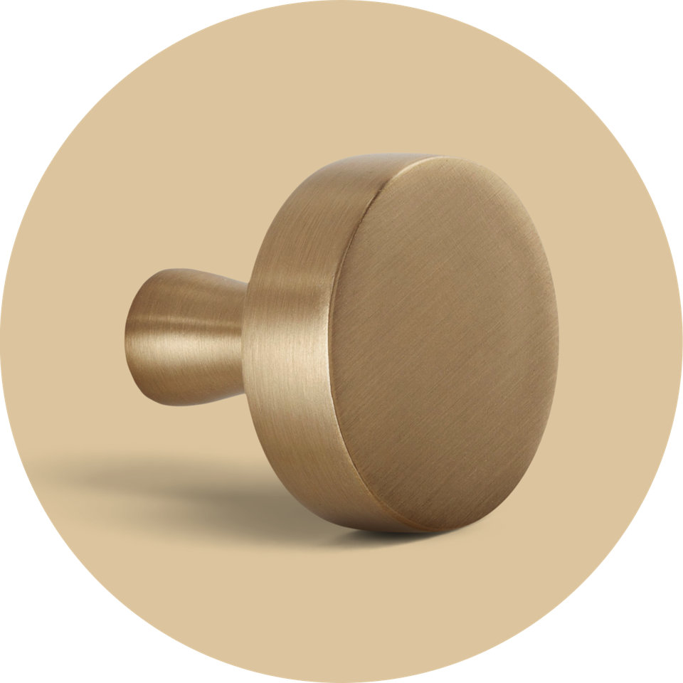 Modern round cabinet knob in a brushed brass finish.