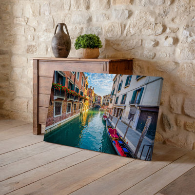 Toile une scène de canal vénitien serein pendant la journée avec un art mural, voie d'eau étroite bordée de bâtiments historiques ornés d'art mural