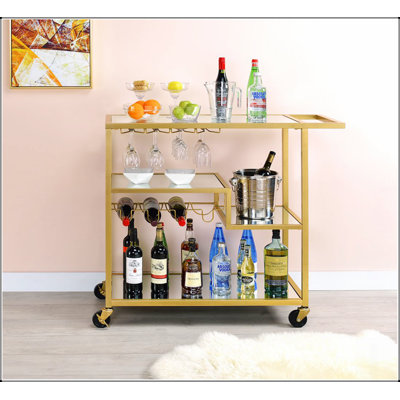Chariot de service Adamsen avec miroir et finition champagne avec porte-bouteilles et porte-verres à pied, parfait pour les réceptions et un rangement élégant.