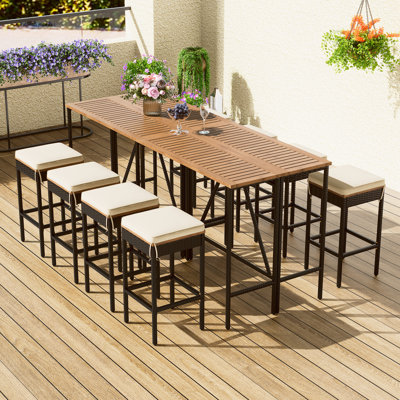 Table de jardin résistante aux intempéries et huit tabourets avec coussins moelleux en bois.