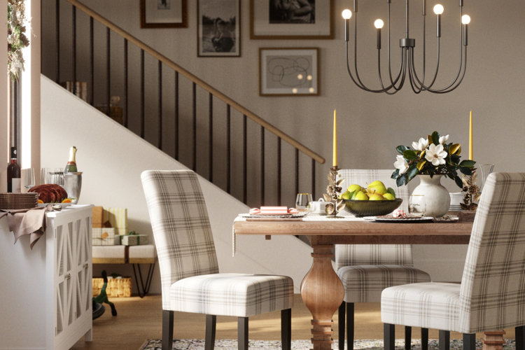 wood dining table with plaid dining chairs and a festive tablescape next to a sideboard topped with a holiday dinner
