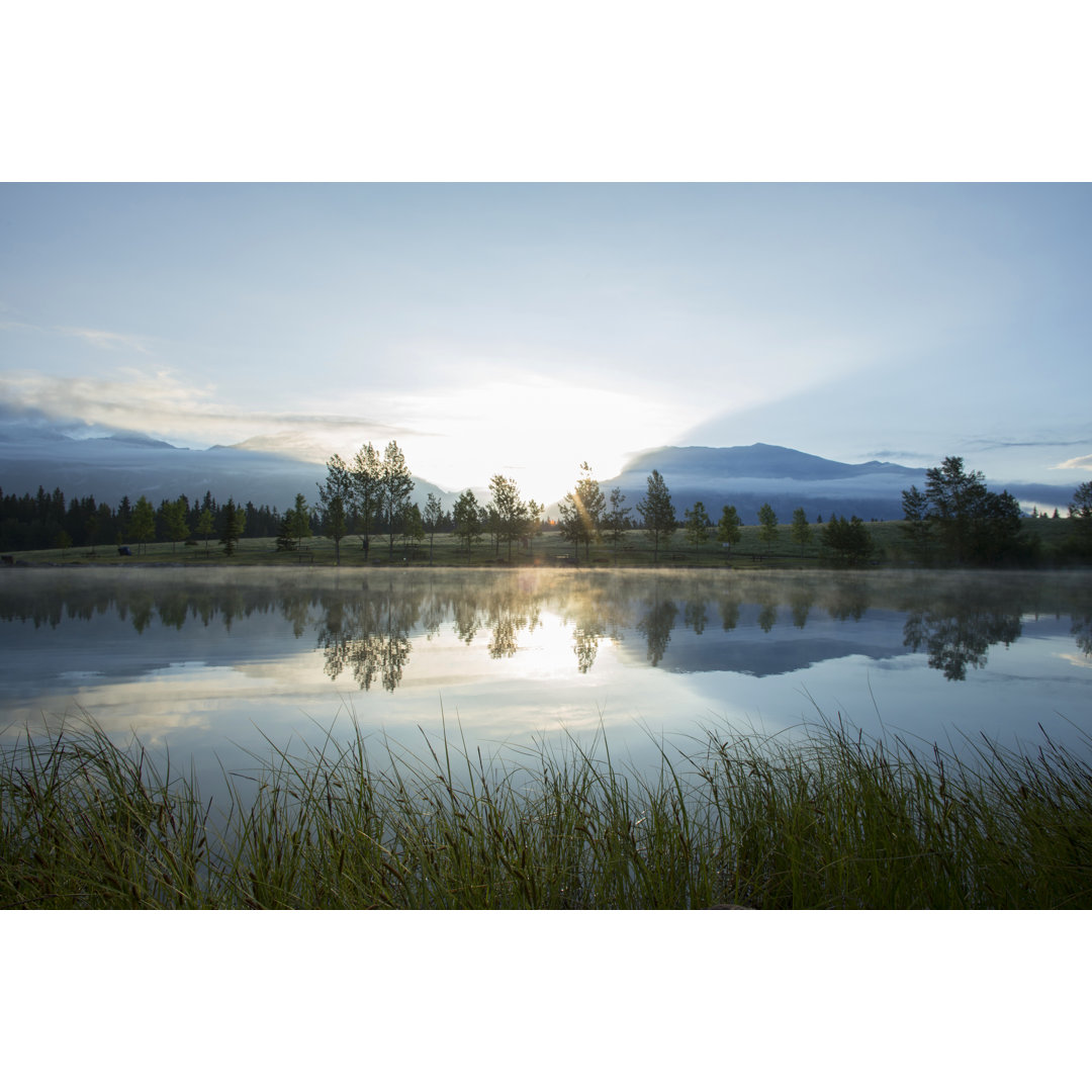 Perfekte Spiegelung von Wald und Bergen im See bei Sonnenaufgang