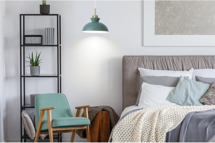 modern bedroom with green swag pendant light next to mint green accent chair and open shelving