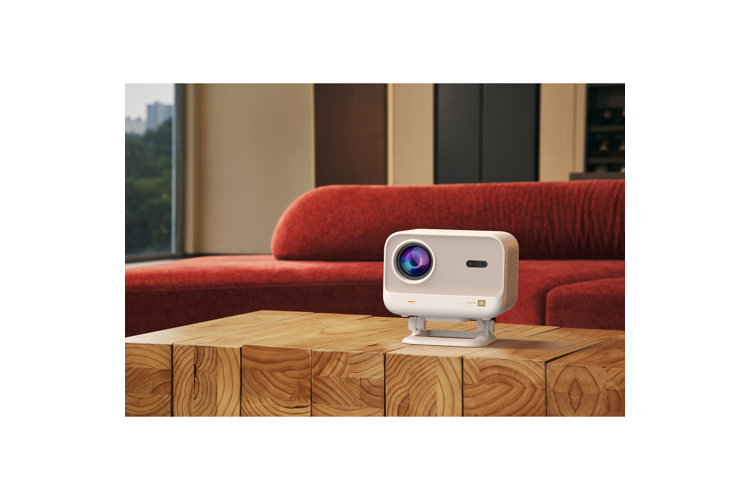 White projector on a wood table in front of an orange sofa