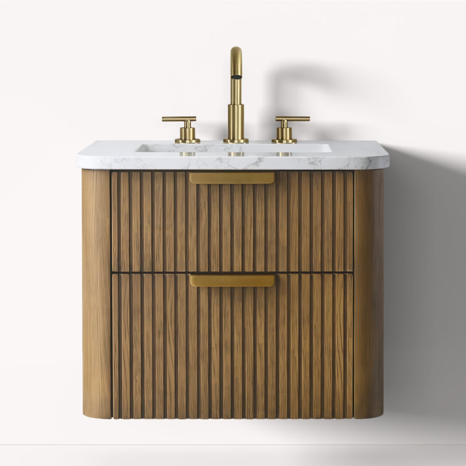 Bathroom vanity with marble top, gold faucet, and reeded wood drawers.