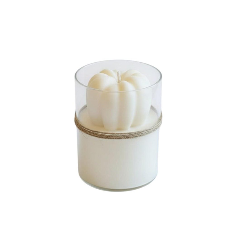 Bougie miniature parfumée à la citrouille et à la pomme, couleur ivoire, dans un pot en verre transparent.