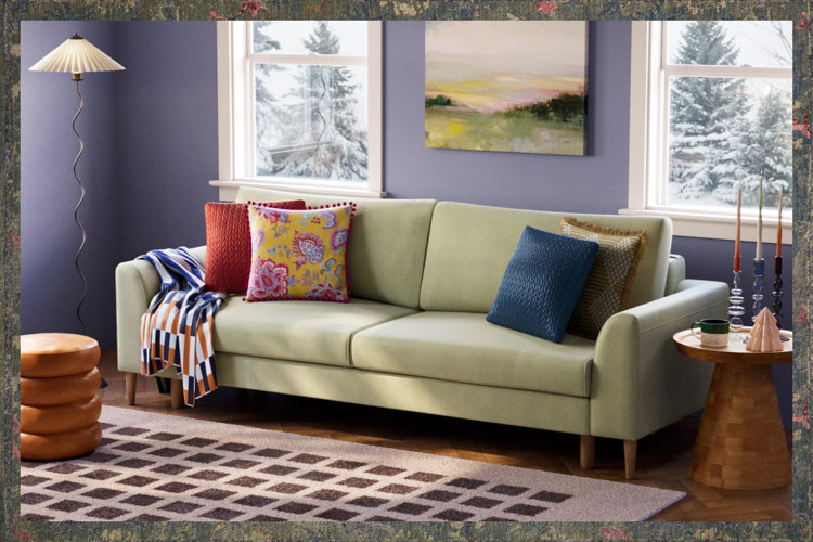 cozy living room with a green velvet sofa, patterned throw pillows, checkered area rug, and a wood side table