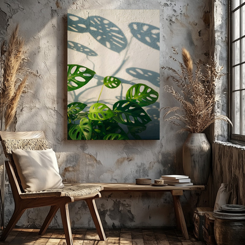 Toile, composition de gros plan avec grandes feuilles de Monstera lustrées, art mural positionné contre un mur blanc texturé à lumière douce