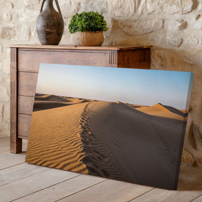 Toile, "Un vaste paysage désertique sous un ciel bleu clair", mettant en vedette des dunes de sable ondulées avec des courbes douces