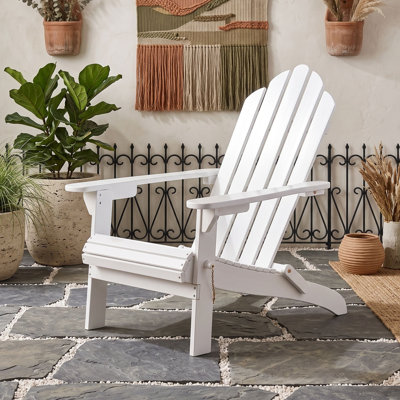 Chaise Adirondack pliable en bois d'acacia avec dossier à lattes, larges accoudoirs, idéale pour l'extérieur, sur une terrasse ou au bord d'une piscine.