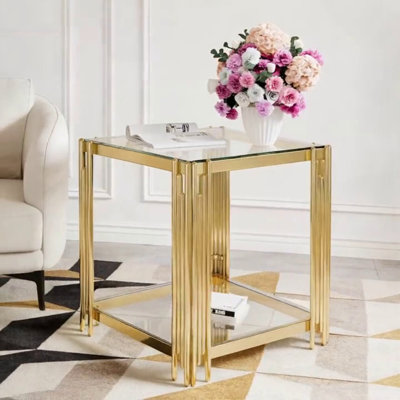 Table basse moderne en verre transparent avec structure asymétrique en métal, finition dorée et tablette inférieure pour un rangement élégant