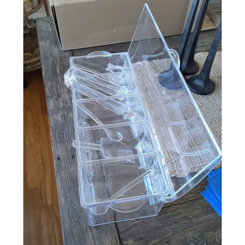 Plateau de service transparent à 5 compartiments pour condiments avec couvercle à charnière et ustensiles de service pour buffets et traiteurs.
