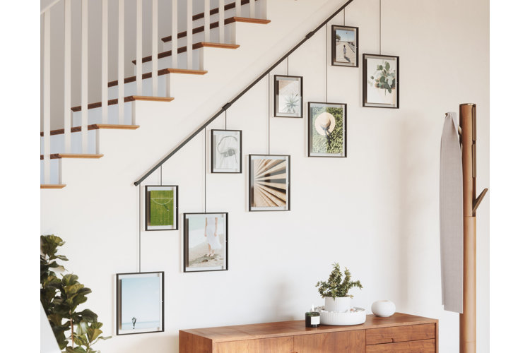 a black picture rail with black picture frames mounted on the side of a staircase wall