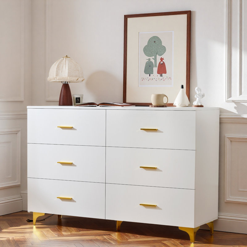 Commode moderne avec 6 tiroirs, poignées dorées et pieds triangulaires dorés