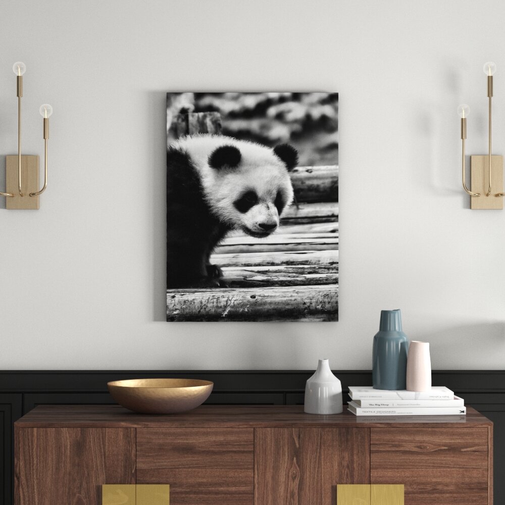 Leinwandbild Niedlicher junger Panda auf Holzstämmen in Monochrom