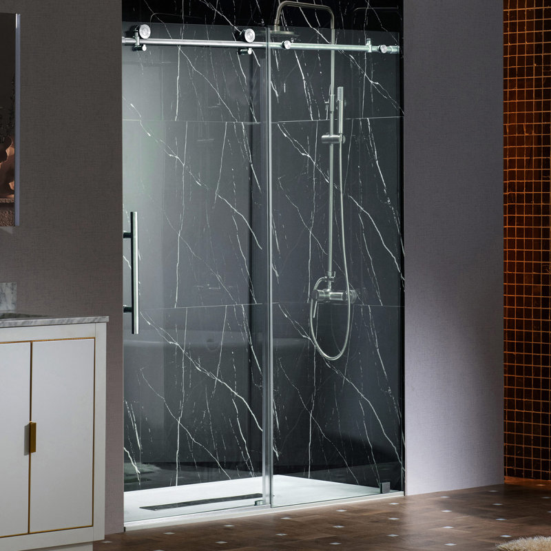 Frameless sliding glass shower door with chrome hardware and handle, installed in a black marble-look tiled shower.