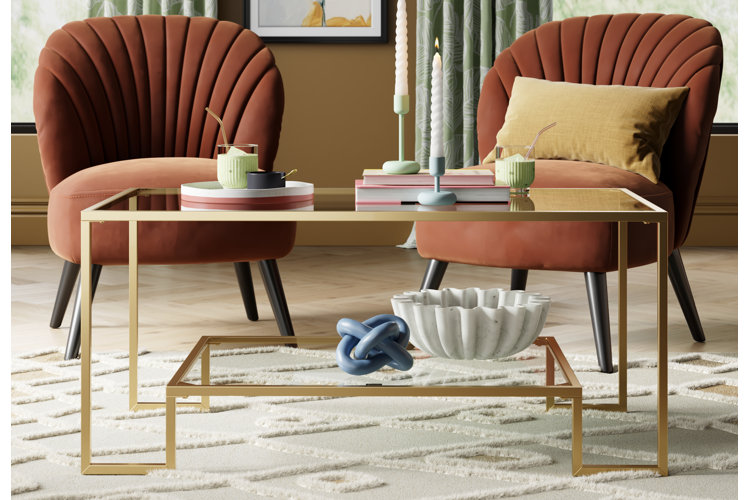 art deco gold framed coffee table and tufted orange chairs filled with beautiful chunky decor