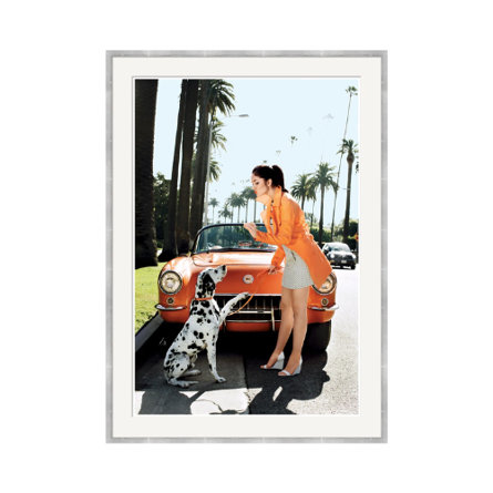 Woman in orange jacket with Dalmatian dog and orange convertible car.
