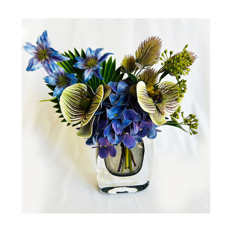 Arrangement de fleurs artificielles dans un vase en verre lesté