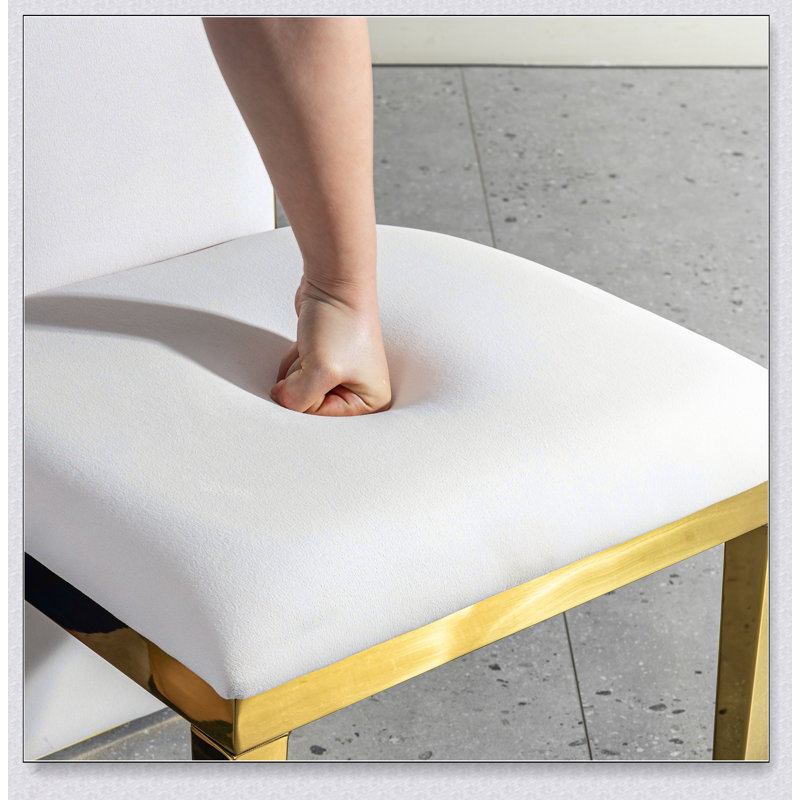 Ensemble de table de salle à manger élégant en acier inoxydable doré avec chaises en tissu blanc, parfait pour les intérieurs contemporains et les petits espaces.