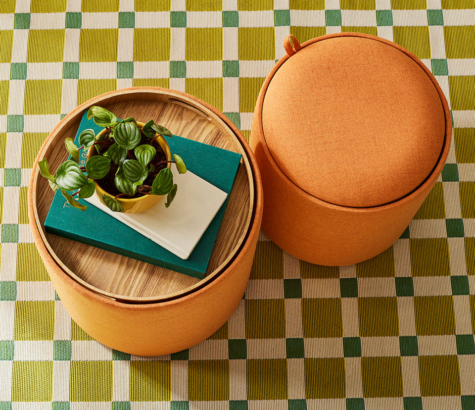 Overhead view of a round orange fabric ottoman with a removable wooden tray lid holding a small potted plant.