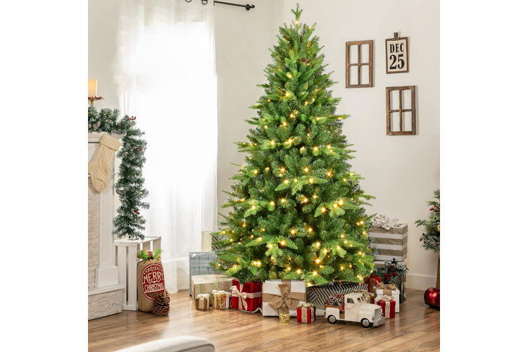 christmas tree with white lights and presents under the tree next to a fireplace