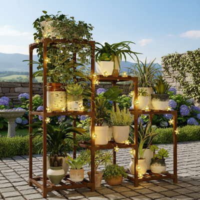 This Three-Tiered Wooden Trapezoidal Plant Stand Features A Battery-Powered Fairy Lamp That Can Hold Up To 7 Potted Plants. It