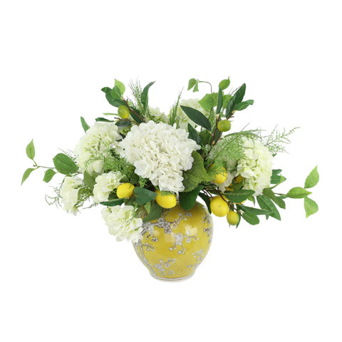 Artificial white hydrangea floral arrangement with decorative lemons in a yellow ceramic vase with white cherry blossom patterns.