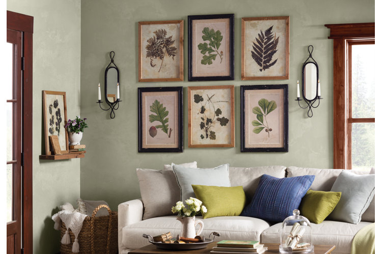nature-inspired living room with a gallery wall filled with botanical prints and artworks above a beige sofa filled with green and blue throw pillows