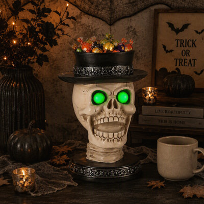 Bougeoir en forme de crâne d'Halloween avec yeux verts lumineux et chapeau haut-de-forme à plumes