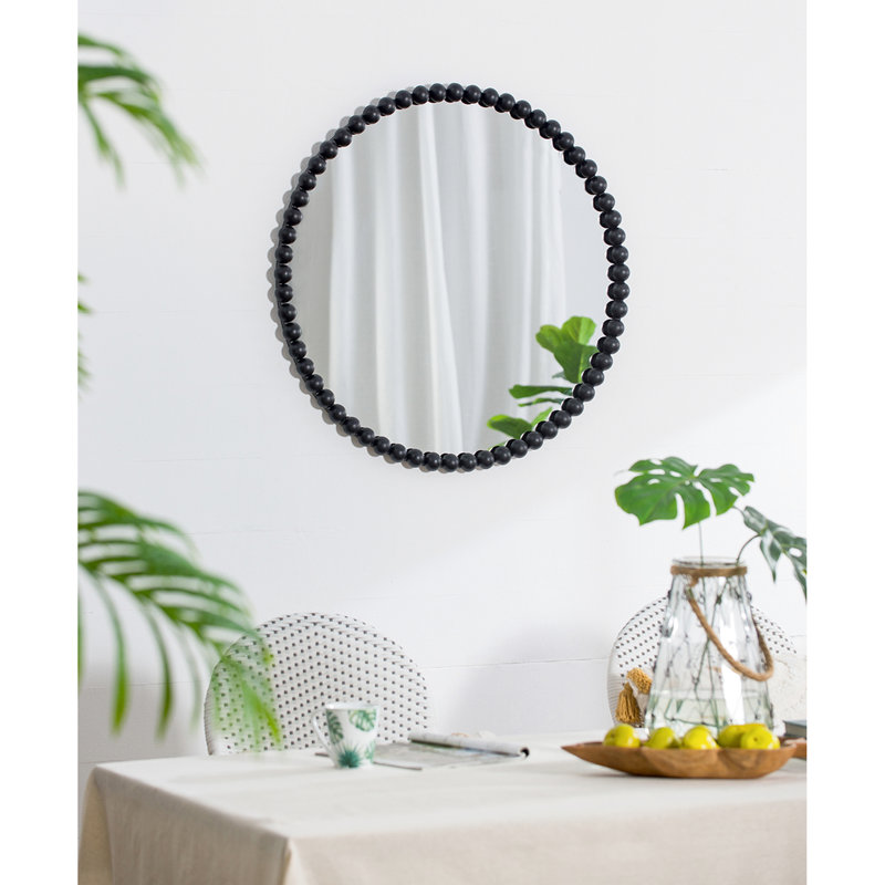 Miroir mural en métal avec cadre perlé reflétant la beauté de la pièce