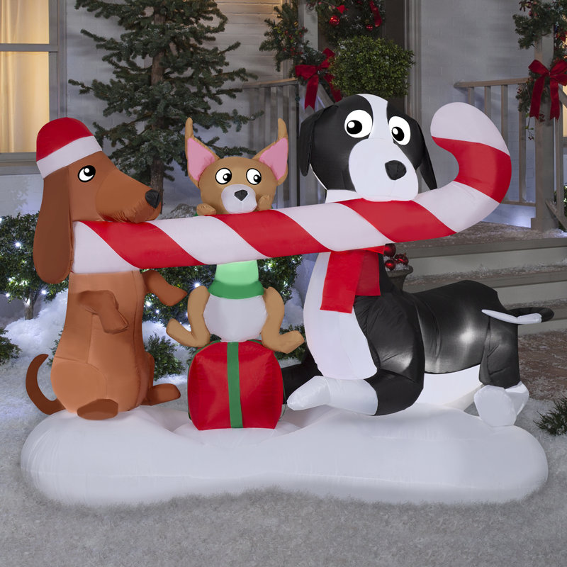 Chiens de Noël gonflables partageant une scène de canne de bonbon