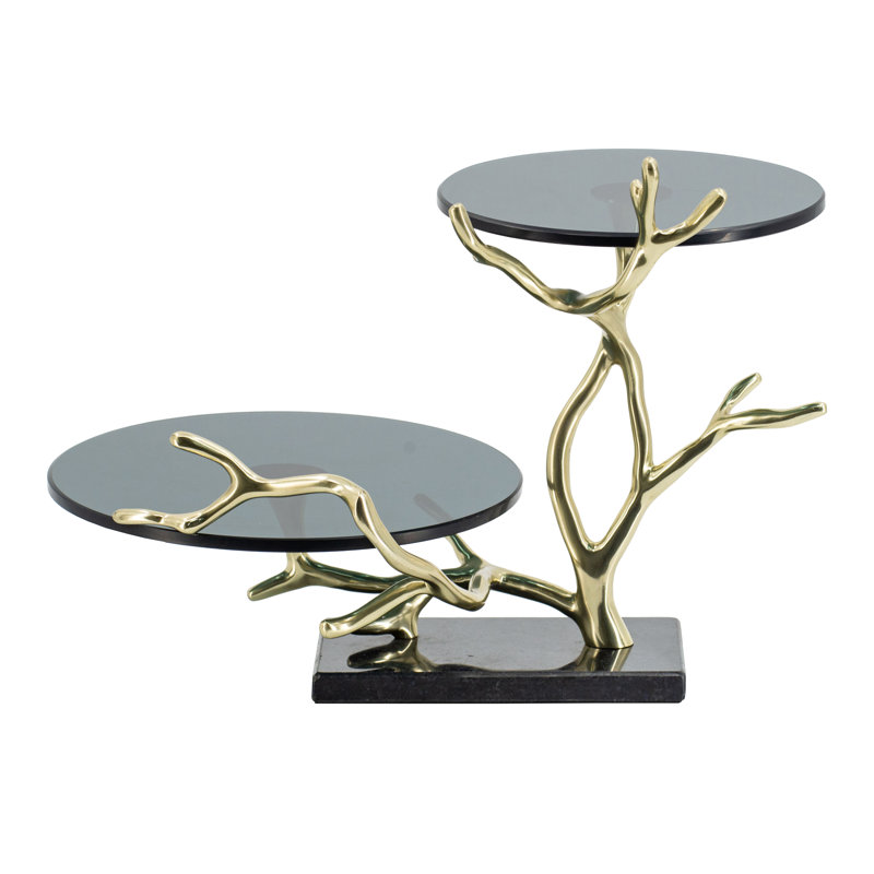 Présentoir à gâteaux à deux étages en forme de branche dorée, avec dessus en verre noir et base en granit.