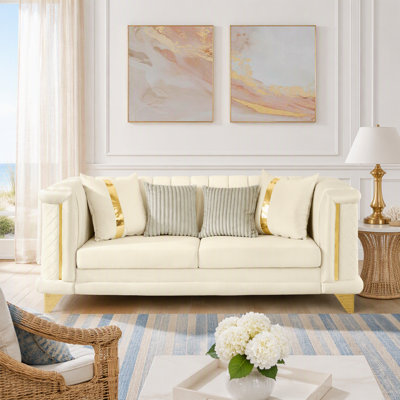 Canapé 3 places en velours luxueux avec motif à rayures capitonnées, structure aux finitions dorées, coussins en mousse à mémoire de forme et texture brodée pour un salon élégant.