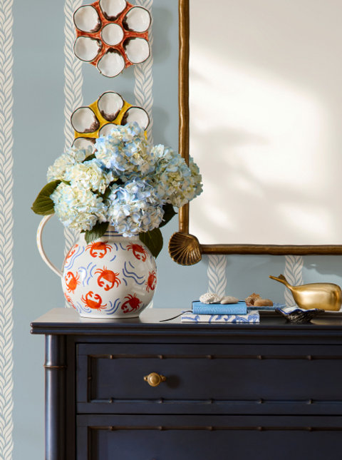 Blue hydrangeas in a crab motif pitcher on a navy chest.
