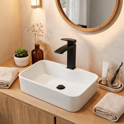 Vasque de salle de bain rectangulaire en céramique blanche de 40,6 cm x 30,5 cm avec robinet et bonde noirs.