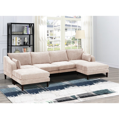 Ensemble de salon modulable 6 pièces en suédine rose poudré, comprenant fauteuils, coussins et canapé. Pieds en bois, style contemporain.
