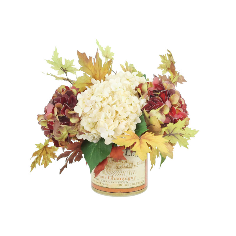 Composition d'hortensias et de feuilles d'automne dans un vase étiqueté